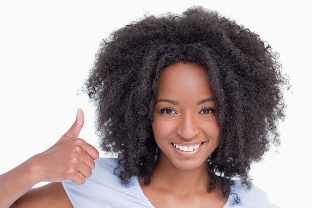 Young woman putting her thumbs up against a white background